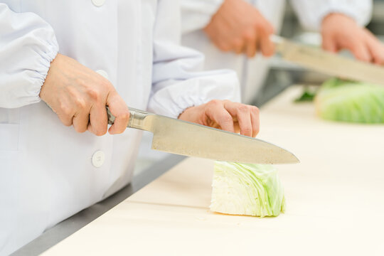 食品加工場で働くキャベツを切るスタッフの手元