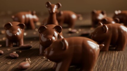 A collection of chocolate bear figurines and a deer figurine on a wooden surface with cocoa beans scattered