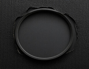  A sleek and modern minimalist composition featuring a smooth black circular element partially revealed through a textured dark grey or black surface with rough edges. Creates a sense of mystery and u