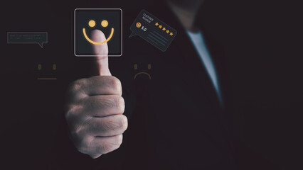 A businessman gives a thumbs-up, touching a virtual screen to select a happy emoticon for a 5-star customer review, symbolizing excellent service and satisfaction.