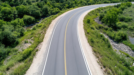 Curved road surrounded by lush greenery and stream, showcasing serene landscape