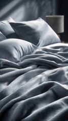 Close-up of a bed dressed in a soft, gray-blue bedding set.  Silky sheets and a draped blanket create a luxurious and inviting atmosphere.  Dim light casts gentle shadows