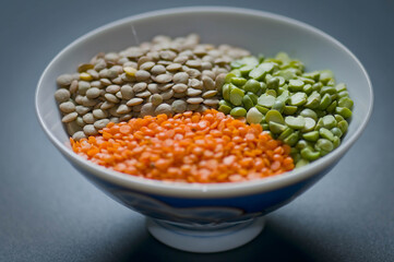 Close-up of red lentils, green split peas, and brown lentils in a bowl—ideal for promoting real food, plant-based protein, healthy diets, and organic living
