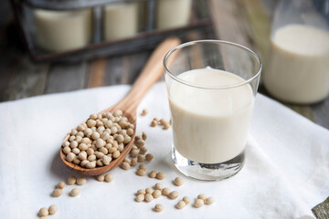 Fresh soy milk in a glass with soybeans and a wooden spoon, locally made local farm. Perfect for diet, healthy, organic, and real food concepts