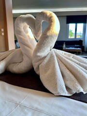 Two towel swans decoration on honeymoon bed in hotel interior bedroom