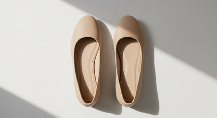 A stylish pair of minimalist nude women flat shoes. Top view of comfortable beige ballet flats for modern female fashion, isolated on white with shadow.