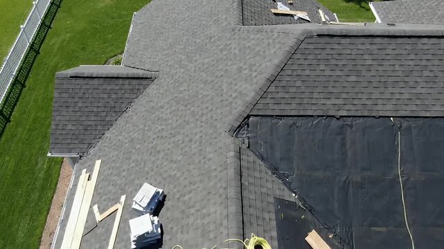 Aerial view of a residential roof under construction with new asphalt shingles being installed over the underlayment Home improvement and roofing repair project
