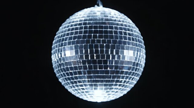 Classic silver mirrored disco ball spinning and glittering with bright light reflections against a pure black background perfect for party dance and music video