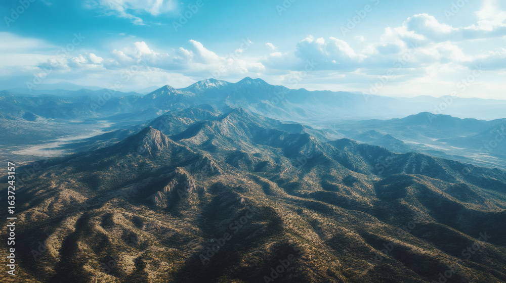 Wall mural high angle view of a rugged mountain range under a partly cloudy sky.