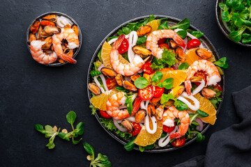 seafood salad with shrimp, mussels, squid, oranges, tomatoes, green lettuce and olemon dressing, top view