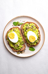 Top view of Avocado toast with boiled egg, sunflower seeds, pumpkin seeds and sesame seeds on plate, Healthy eating