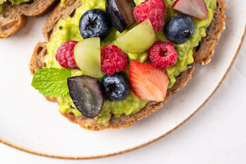 Top view of Avocado toast with strawberry, blueberry, raspberry and grape. Healthy eating