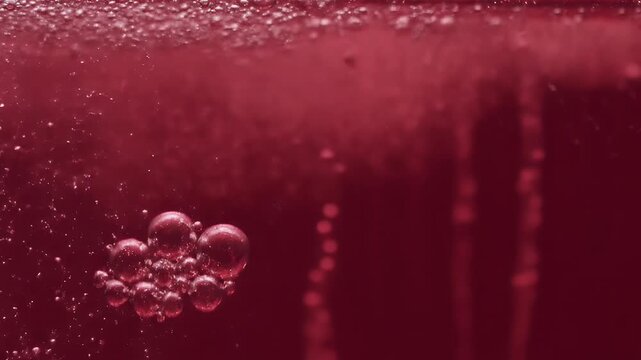 Macro shot of sparkling bubbles rising in a deep red liquid Abstract background of a carbonated beverage like red wine or cherry juice fizzing in extreme close 