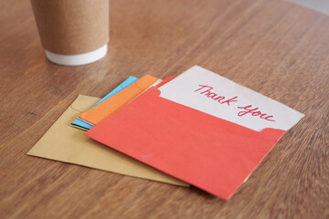 Colorful thank you cards and coffee cup on wooden table