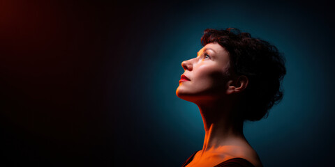 woman gazes upward against a backdrop of contrasting colors, highlighting her features and conveying a sense of introspection and wonder.