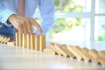 Close-up hand prevents and choose wooden block not falling concepts of financial risk management...