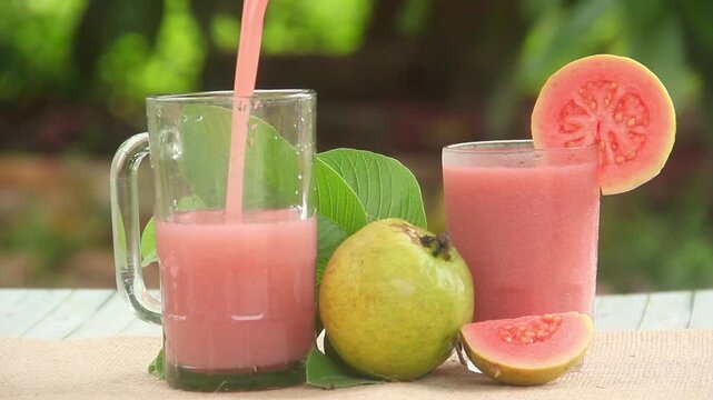 Pouring red guava juice or Psidium guajava into a glass and decorating it with guava slices around it