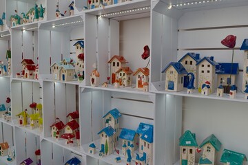 Small store with many colorful pottery ceramic miniature houses standing on shelves for display
