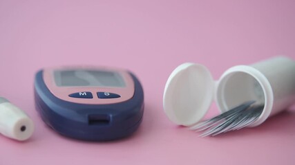 Glucose monitoring device and test strips on pink background