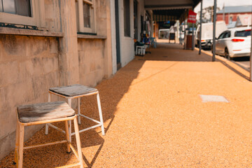 Small stools in semi-shade along the footpath in small town street