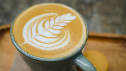 A close-up view of a cup of coffee with intricate latte art in the shape of a leaf