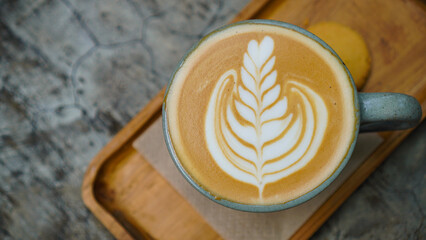 A close-up view of a cup of coffee with intricate latte art in the shape of a leaf