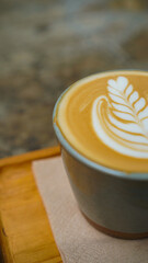 A close-up view of a cup of coffee with intricate latte art in the shape of a leaf
