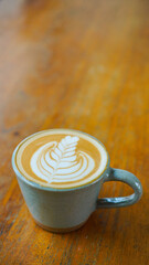 A close-up view of a cup of coffee with intricate latte art in the shape of a leaf