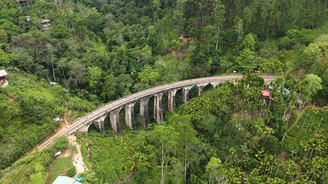 Aerial 4K drone footage of the iconic Nine Arch Bridge near Ella, Sri Lanka. Stunning views of the historic railway viaduct, lush green hills, and scenic train crossing for travel and tourism projects