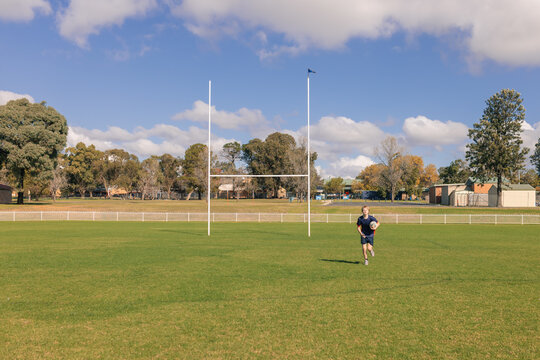 Teenage boy running with rugby ball on field
