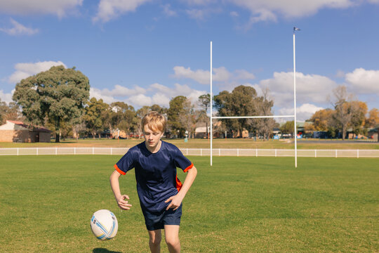 Junior rugby union player chasing runaway ball on field