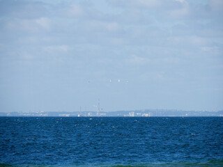 Fototapeta premium Calm blue sea surface with a soft, slightly hazy horizon line and a clear sky above.
