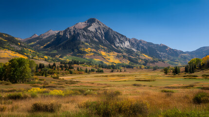 Obraz premium Autumnal mountain range vista, golden meadow, clear sky