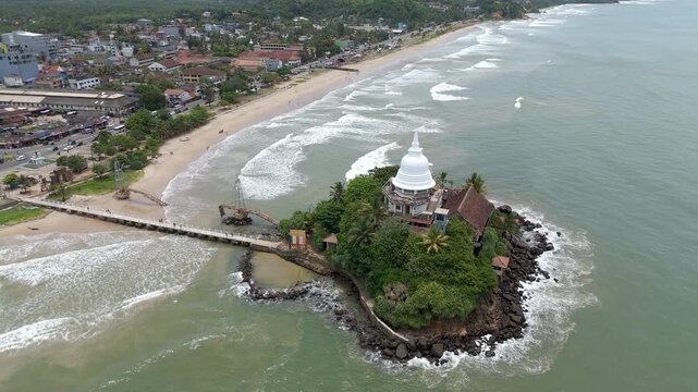 Aerial 4K drone footage of Matara Temple, Sri Lanka. Stunning coastal Buddhist temple with ocean views, lush greenery, and cultural heritage&mdash;perfect for travel, tourism, and spiritual projects.