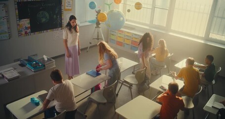 Female Teacher Finishing Lesson, Saying Goodbye to Group of Diverse Kids at the End of School Day. Happy Primary School Children Packing Their Backpacks and Leaving School for Holidays. High Angle.