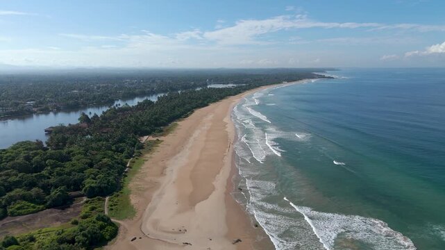 Aerial 4K drone footage of Bentota Beach, Sri Lanka. Beautiful tropical coastline, golden sands, palm trees, and turquoise waters ideal for travel, tourism, beach, and tropical vacation projects.