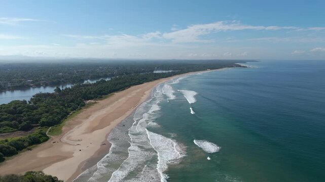 Aerial 4K drone footage of Bentota Beach, Sri Lanka. Beautiful tropical coastline, golden sands, palm trees, and turquoise waters ideal for travel, tourism, beach, and tropical vacation projects.