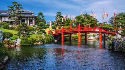 Obraz premium The exterior of a traditional Japanese tea house in a Japanese garden with a wooden bridge over a pond