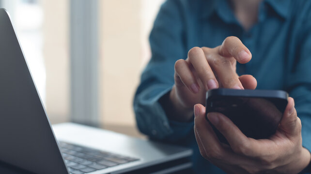 Businesswoman using mobile smart phone, working on laptop computer at office, close up. Asian woman using smartphone searching the information, surfing tne internet with laptop on office table - Powered by Adobe