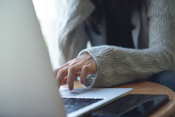 Obraz premium Closeup, young woman sitting at table, working on laptop computer at coffee shop. Female freelancer online working, surfing the internet, remote work from home office, freelance lifestyle
