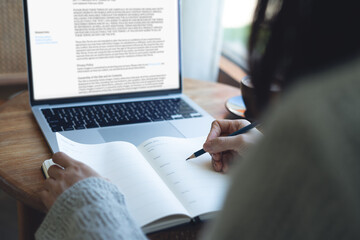 Business woman hand writing with pencil planning event on notebook. Job schedule, event planning, to do list and reminder, E-learning. Woman working on laptop and taking note on office desk, close up