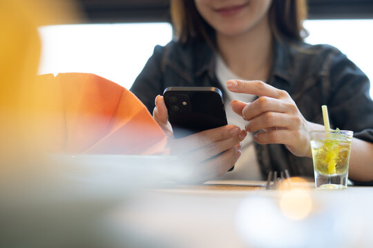 Young asian woman scanning the QR code with mobile phone and order foods at the restaurant. Woman using smartphone for social media, surfing internet during wating for foods, close up