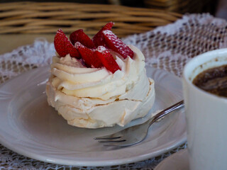 Close-up of a perfectly crafted meringue dessert crowned with fresh, juicy strawberries, presented on a white plate.