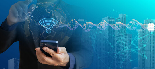 Businessman using smartphone with global WiFi network connection, smart city background, and digital data wave. Modern wireless communication, IoT technology