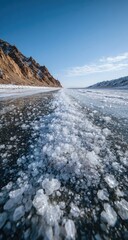 Obraz premium Frozen lake road stretches into a mountain range under a clear sky