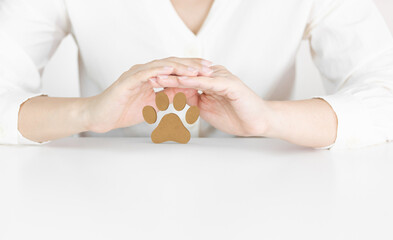 Obraz premium Hands Protecting Wooden Paw Print Symbolizing Pet Care, Safety and Animal Welfare