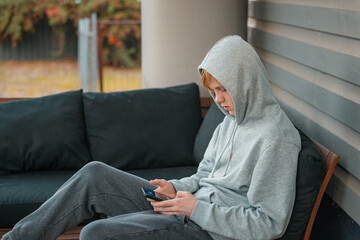 Teenage boy wearing grey hoodie playing games on mobile phone © Caseyjadew