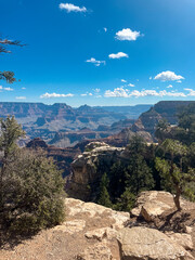 Wide-angle view of the Grand Canyon with layered rock formations and vibrant blue sky in September sunlight.