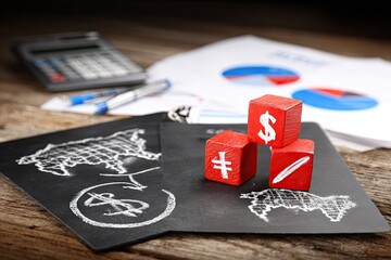 Red blocks with currency symbols atop paperwork and diagrams