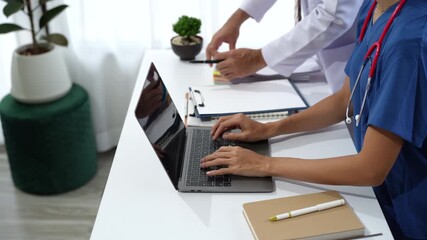 Professional female doctor wearing white lab coat and stethoscope documenting patient information on clipboard near laptop in clinic workspace. Medicine and health care concept - Powered by Adobe